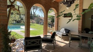 A covered patio with brick arches, outdoor furniture, and a view of a swimming pool. - Le Balze Charming Apartment in villa, private garden, 10 min from Perugia Centre (Perugia)