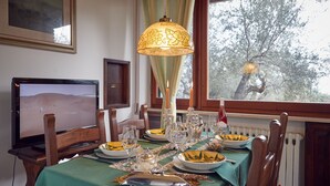 A dining table set for four with a green tablecloth, candles, and a television displaying a desert landscape. - Le Balze Charming Apartment in villa, private garden, 10 min from Perugia Centre (Perugia)