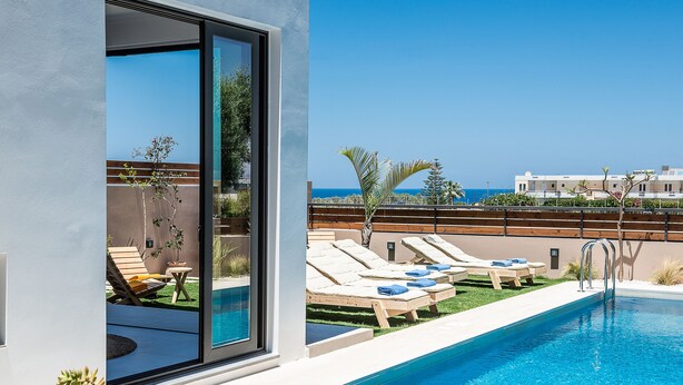 Un espace piscine moderne, doté de chaises longues et offrant une vue dégagée sur la mer.