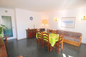 Un espace repas comprenant une table, des chaises, un canapé, un meuble et une lampe.