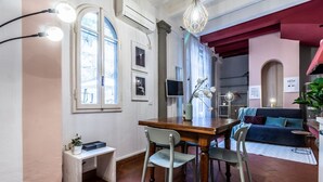 A dining area with a wooden table and chairs, a small bench, a potted plant, and a hanging light fixture. - Wine Apartments Florence Vernaccia (Firenze)
