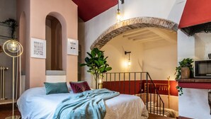A bedroom with a bed, a red wall, a staircase, and a TV. - Wine Apartments Florence Vernaccia (Firenze)