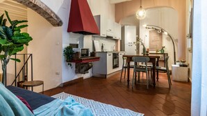 A compact kitchen with modern appliances, a dining area with a table and chairs, and a large plant in the corner. - Wine Apartments Florence Vernaccia (Firenze)