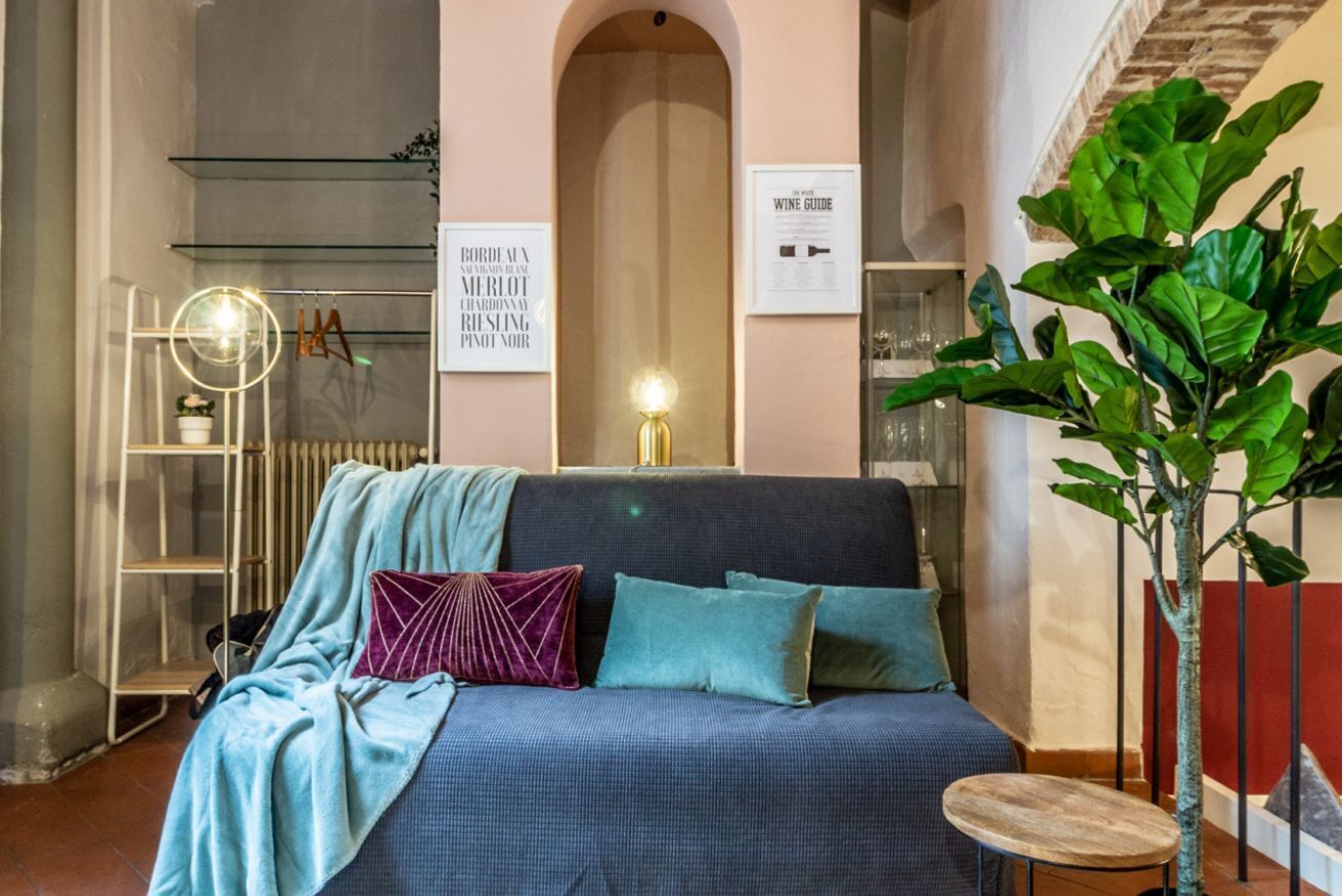 Una habitación acogedora con sofá, una mesita redonda, un radiador y una planta grande.