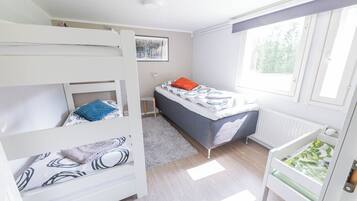 Cozy bedroom with a bunk bed and single bed, featuring a large window and radiator for comfort.