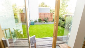 A balcony with a view of a well-maintained lawn and a wooden fence.