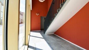 A modern interior with a staircase, a glass door, and a red wall.