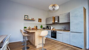 A modern kitchen with a wooden island, bar stools, a built-in oven, and a pendant light.