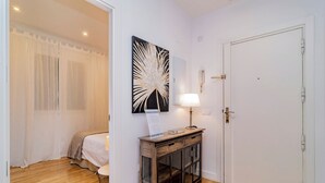 A bedroom with a bed, a bedside table with a lamp, a wall-mounted artwork, and a door. - Deluxe Apartment Juan Bravo Suites I (Madrid)