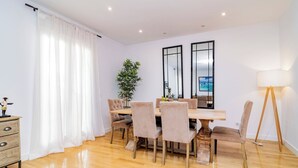 A dining area with a wooden table, four chairs, a potted plant, and a lamp. - Deluxe Apartment Juan Bravo Suites I (Madrid)