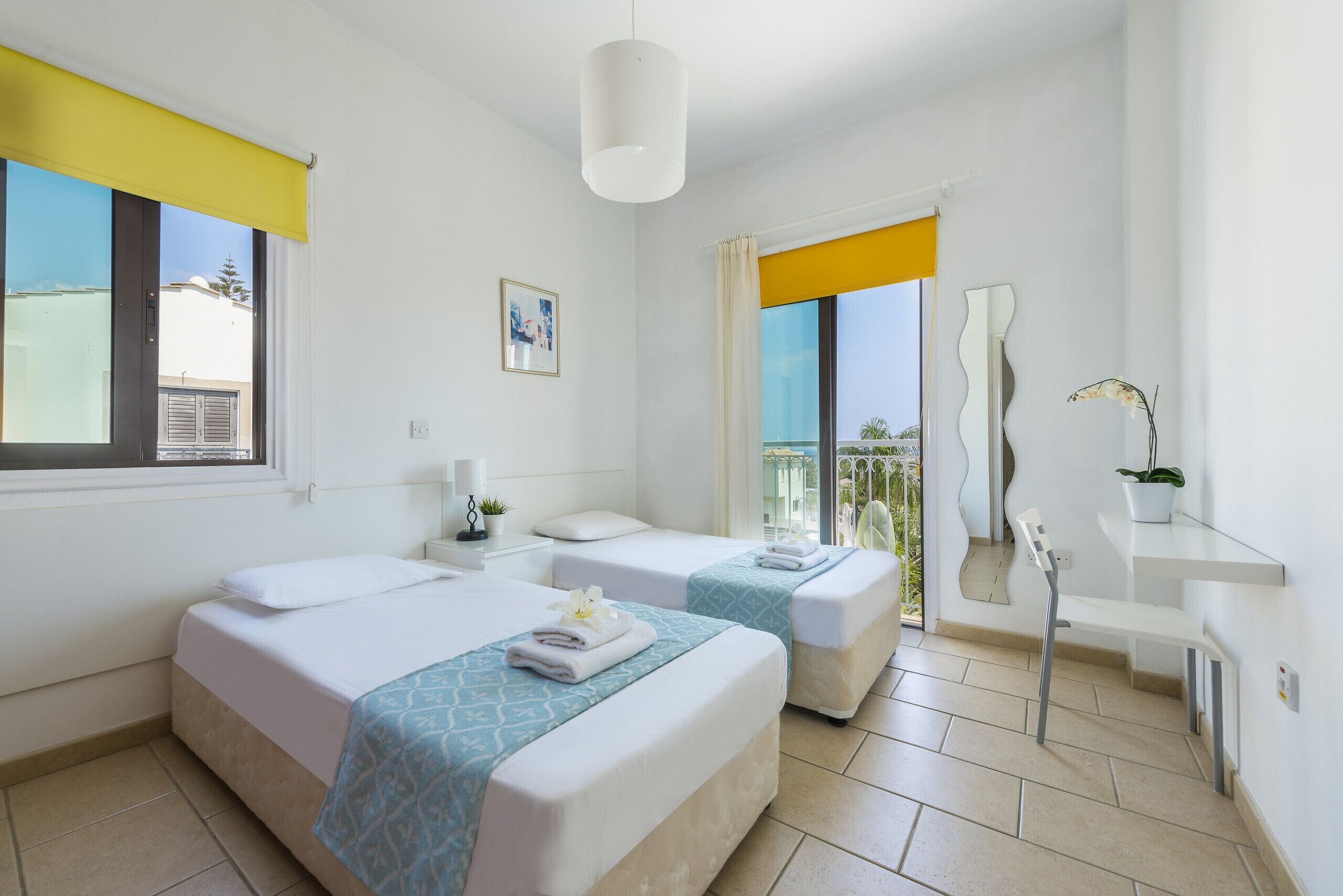 A hotel room with two beds, a bathroom, a balcony, and a view of the outside.