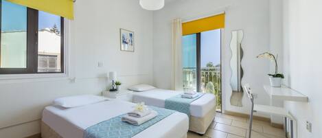 A hotel room with two beds, a bathroom, a balcony, and a view of the outside.
