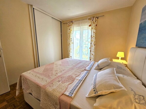 Une chambre à coucher avec un lit, une table de chevet, une lampe et une fenêtre avec des rideaux.