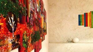 A room with a large abstract painting on the wall, a white spherical object on a shelf, and a bed with a peach-colored pillow. - "G&G Pignasecca" house in the heart of central Naples (Napoli)