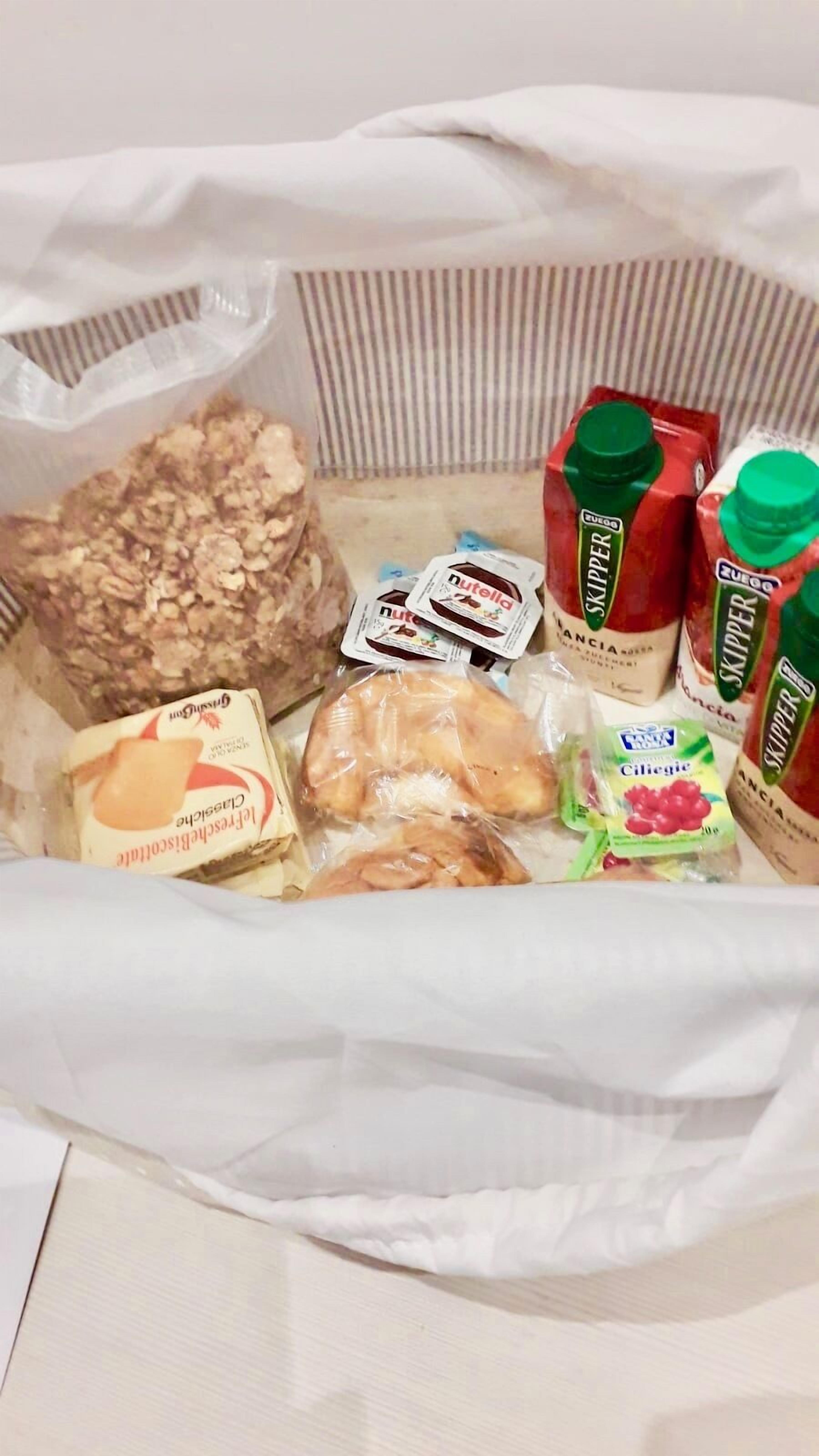 Diverse varietà di cibo, tra cui cereali, Nutella, latte a marchio Skipper e una confezione di ciliegie.