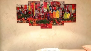 A bedroom with a bed, a wall-mounted artwork, and a small table with papers. - "G&G Pignasecca" house in the heart of central Naples (Napoli)
