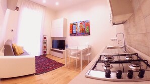 A modern kitchen with a gas stove, white cabinets, and a dining area with a table and chairs. - "G&G Pignasecca" house in the heart of central Naples (Napoli)