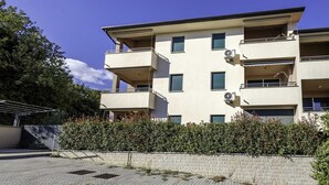 Un edifici residencial de diversos pisos amb balcons, aires condicionadors i un carrer empedrat.