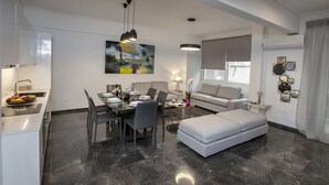Un espace de vie moderne comprenant un coin repas, un canapé et un pouf.