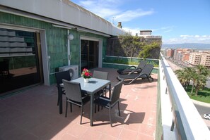 Un balcone con tavolo e sedie, una pianta in vaso e vista sulla città.