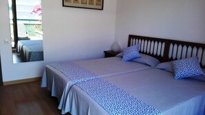Un letto matrimoniale con copriletto decorato, due cuscini, un comodino con lampada e un certificato incorniciato appeso al muro.