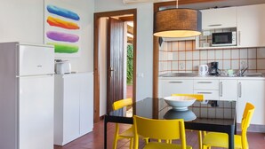 Een moderne keuken met witte kasten, een magnetron, en een eethoek met een zwarte tafel en gele stoelen.