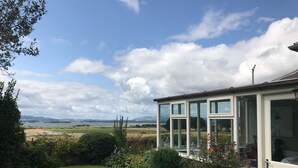Une maison dotée d’une véranda donnant sur un espace verdoyant et un lac.