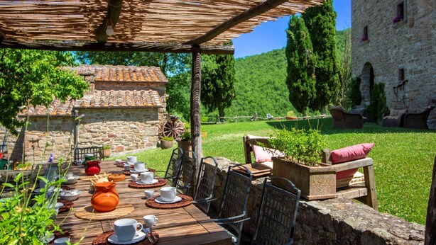 An outdoor dining area with a table set for a meal, surrounded by stone walls and greenery. - Wonderful private villa for 16 people with WIFI, private pool and TV (Arezzo)