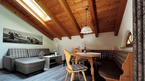 Un acogedor espacio tipo loft con techo de madera, una mesa de comedor con sillas, un sofá y un banco.