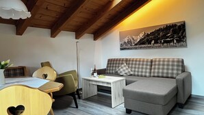Una sala de estar acogedora con un sofá, una mesa, una silla y un cuadro en la pared.