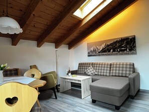 Una sala de estar acogedora con un sofá, una mesa, una silla y un cuadro en la pared.