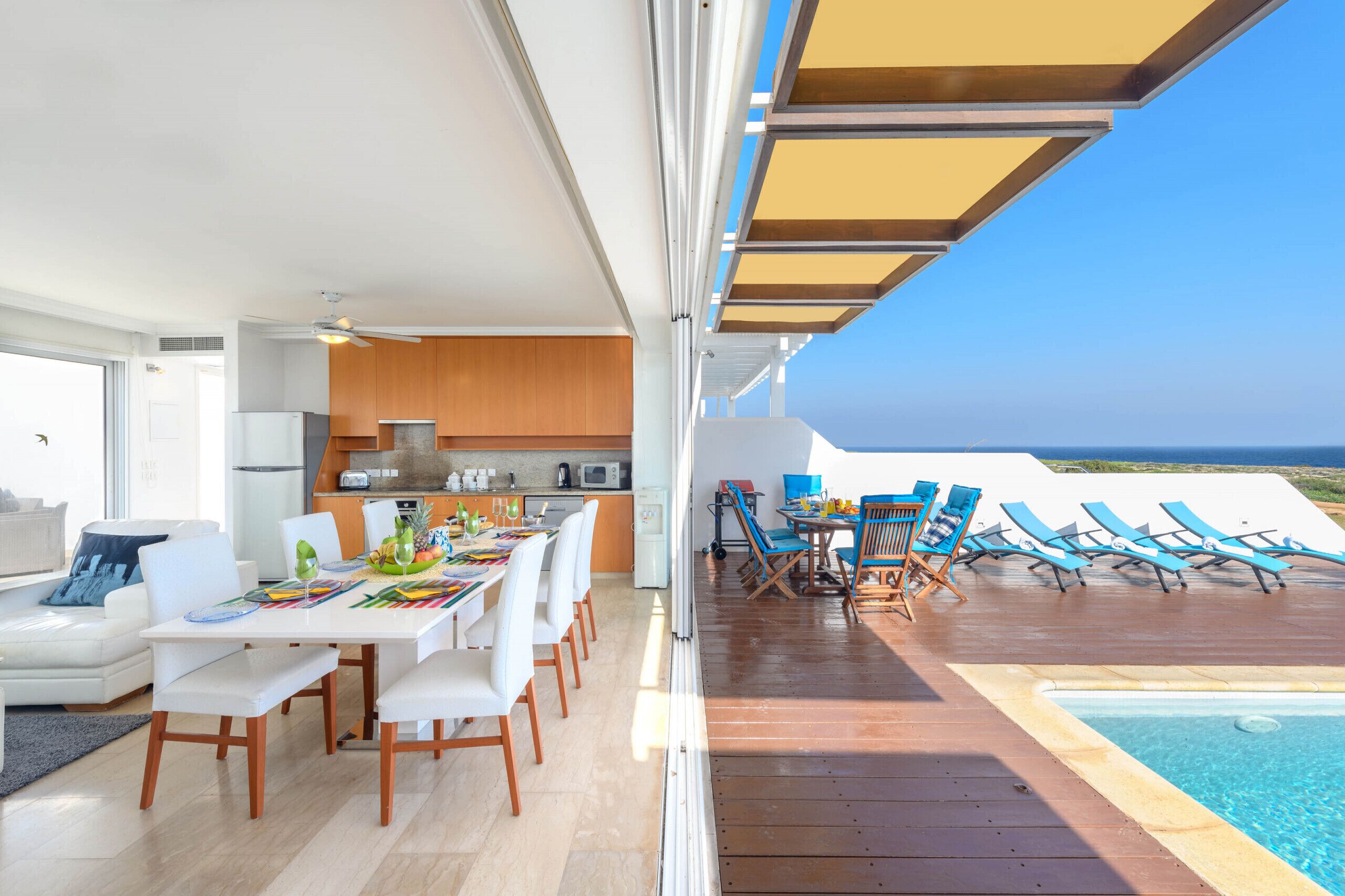 A modern kitchen with white cabinets and a dining area with white chairs.