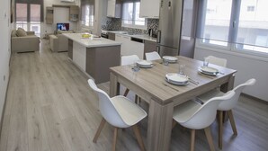 Een moderne keuken met een centraal eiland, witte stoelen en een eettafel gedekt voor vier personen.