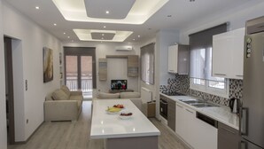 Een moderne keuken met een centraal eiland, inbouwapparatuur en een zithoek met een bank.