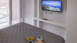 Een hotelkamer met een bed, een televisie aan de muur en ontbijtartikelen op een dienblad.