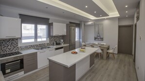 Een moderne keuken met een centraal eiland, inbouwapparatuur en een eethoek met een tafel en stoelen.