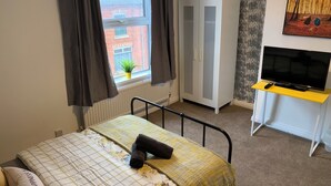 A bedroom with a bed, a wardrobe, a desk with a TV, and a window with curtains. - Gordon House. (Kettering)