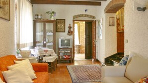 A living room with a sofa, a television, a table with a vase, and a patterned rug.