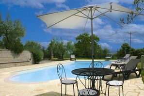 A swimming pool with lounge chairs and a table, surrounded by a stone wall and trees. - Stunning private villa for 8 people with private pool, WIFI, TV and pets allowed, close to Arezzo (Badia Al Pino)