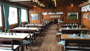 Ein Restaurant mit Holzvertäfelungen, mehreren Tischen und hängenden Lampen.