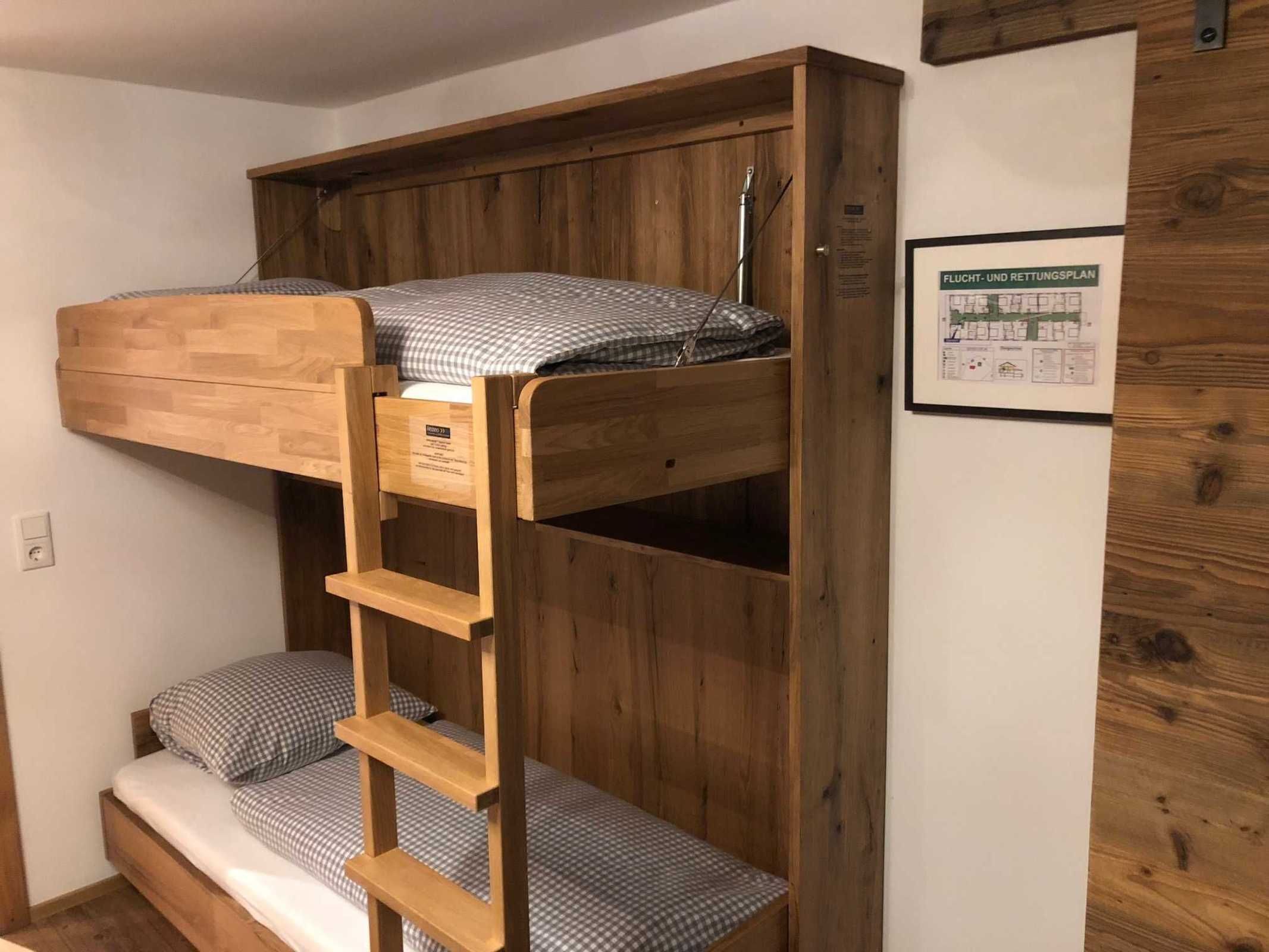 Een stapelbed met een ladder, houten wanden en een ingelijst plan aan de muur.