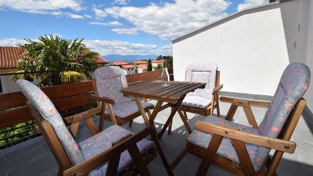 Un patio con mobiliario de madera y una pared blanca.