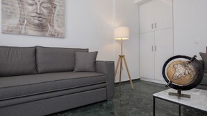 Una sala de estar moderna con un sofá gris, una lámpara de pie, un globo terráqueo sobre una mesa y una pintura de Buda en la pared.