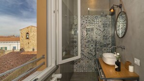 A bathroom with a large window, a white sink, patterned tiles, and a wooden vanity. - Mediceo 42 - Deluxe Double Room (Pisa)