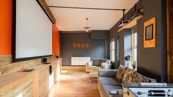A modern living room with a sofa, a foosball table, and a wooden reception desk.