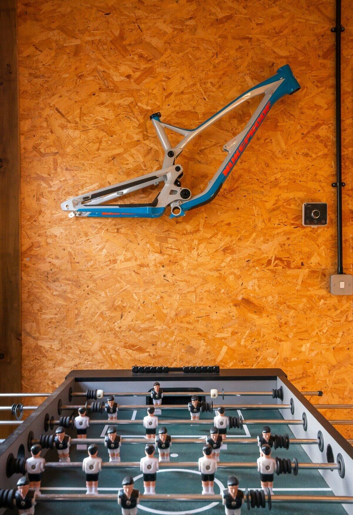 Een tafelvoetbalspel en een fiets bevestigd aan een houten wand.