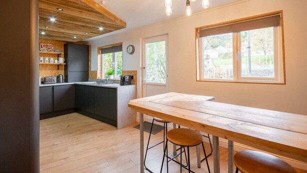 Une cuisine moderne avec des éléments en bois, un îlot central et des tabourets de bar.