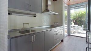 A modern kitchen with grey cabinets, a stainless steel sink, and a large window overlooking a patio area. - Villa Baena by FeelFree Rentals (San Sebastián)