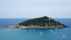 A small island with a lighthouse, surrounded by calm waters and several boats. - Villa Baena by FeelFree Rentals (San Sebastián)