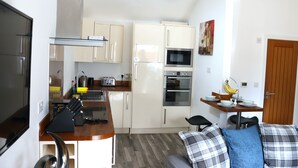 A compact kitchen with white cabinets, a microwave, oven, and a small dining area with a table and chairs.